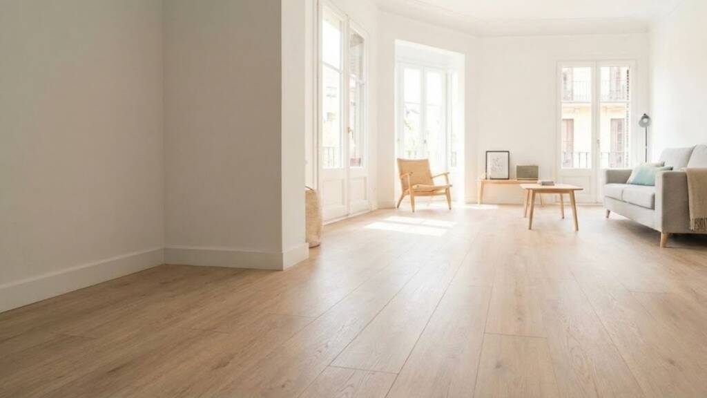 Retiramos un viejo terrazo frío para instalar un suelo laminado de gran formato que ha multiplicado la luz natural de este salón sin necesidad de picar el suelo existente.